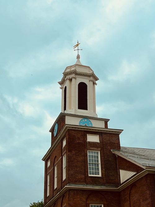 Free Classic brick church tower beneath a cloudy blue sky, exuding timeless architecture. Stock Photo