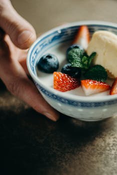Close-up of a yogurt bowl with fresh strawberries, blueberries, and mint leaves. Perfect healthy breakfast.