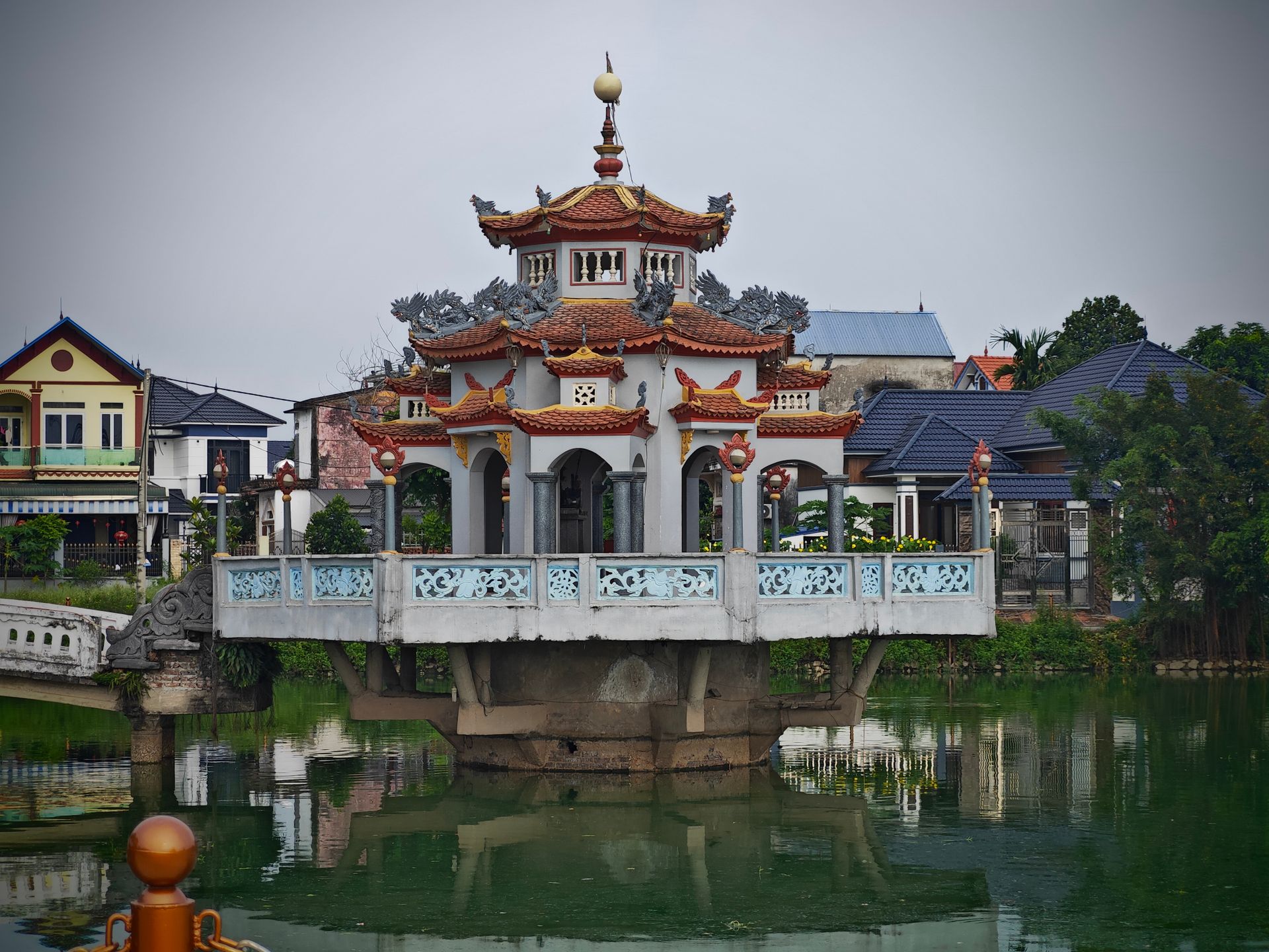 Beautiful oriental pavilion with intricate roof design over serene lake reflecting architecture.