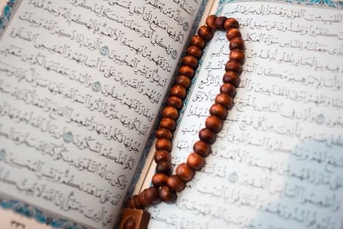 Free An open Quran page with wooden prayer beads, showcasing Islamic calligraphy and spiritual symbolism. Stock Photo
