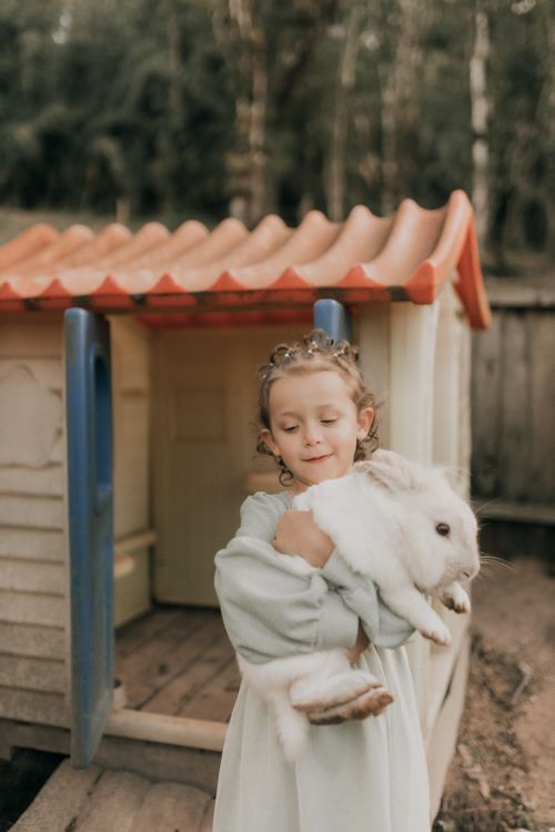 Child hugging white rabbit near playhouse outdoors · Free Stock Photo