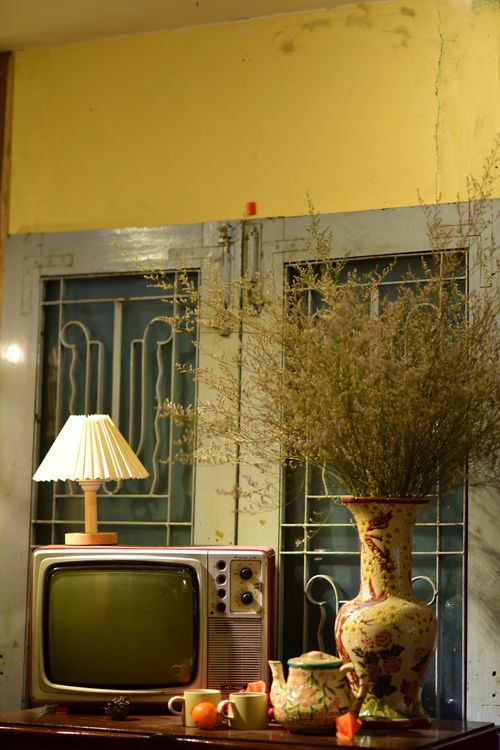 Free A nostalgic room with a vintage TV, table lamp, and floral vase arrangement. Stock Photo