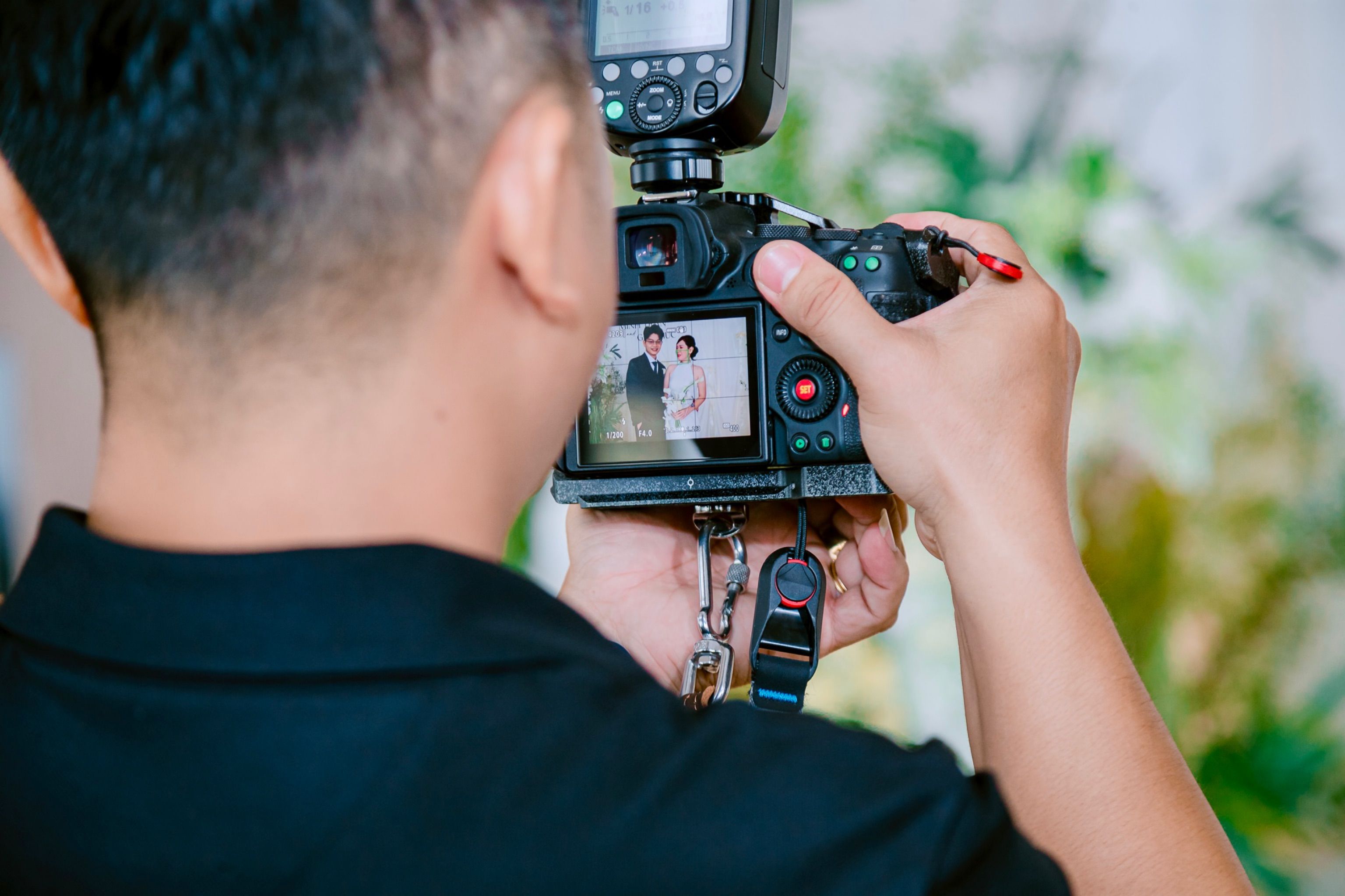 A photographer shooting a couple, the frame showing on the camera screen