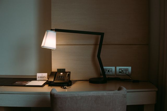 A modern hotel room desk featuring a stylish lamp, telephone, and stationery set. Related image for Smart Hotels: What Is Changing Across Global Hospitality.