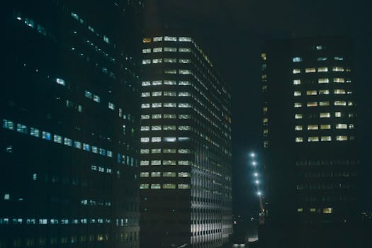 Night view of illuminated office buildings in a city, creating a mysterious urban atmosphere.