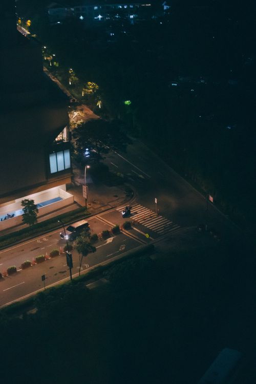 Free Aerial view of a city street at night with dim lighting and a visible crosswalk. Stock Photo