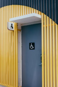 Stylish accessible restroom door with vibrant yellow and gray color scheme and wheelchair symbol signage.