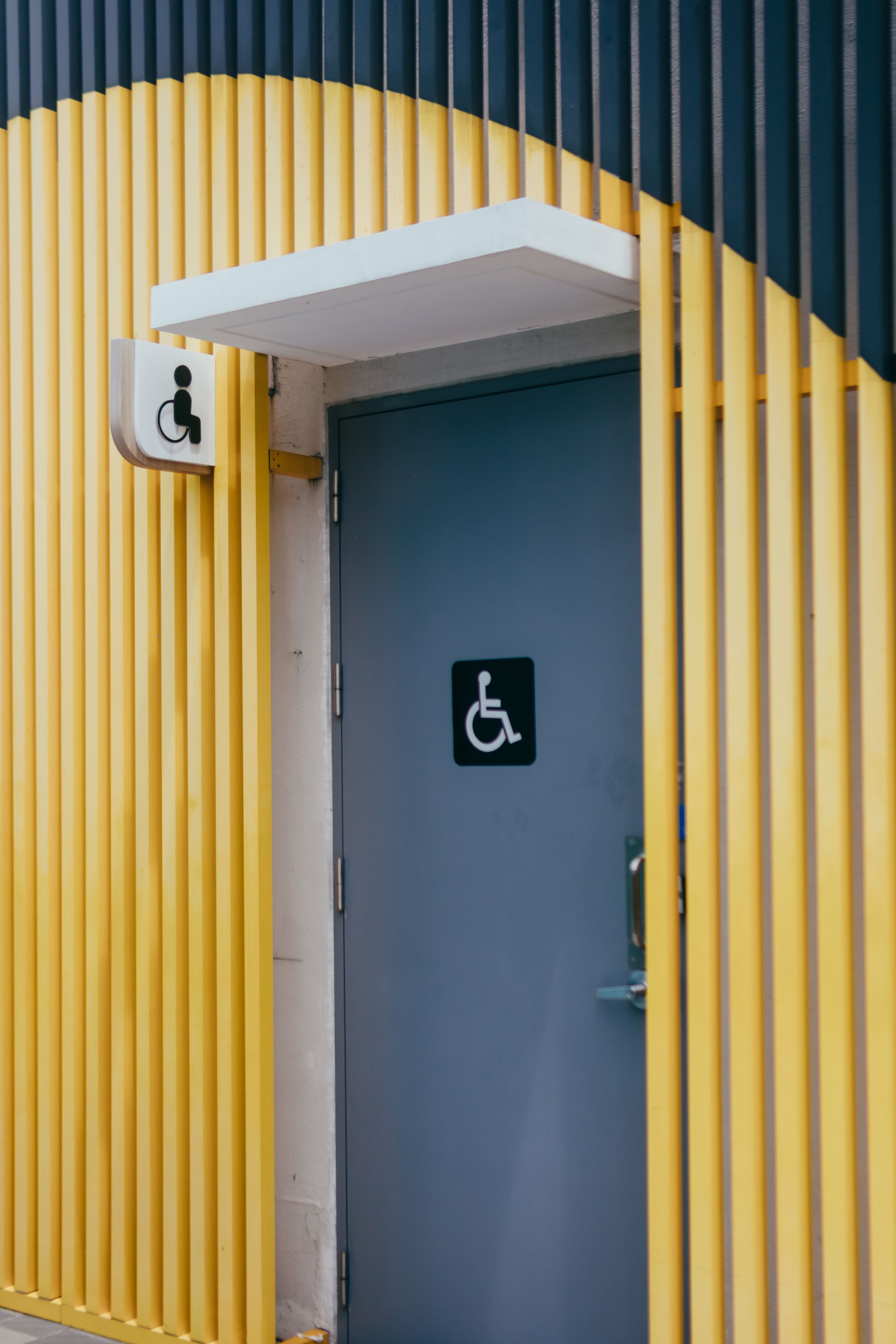 Accessible restroom doorway with yellow and grey wall finishes