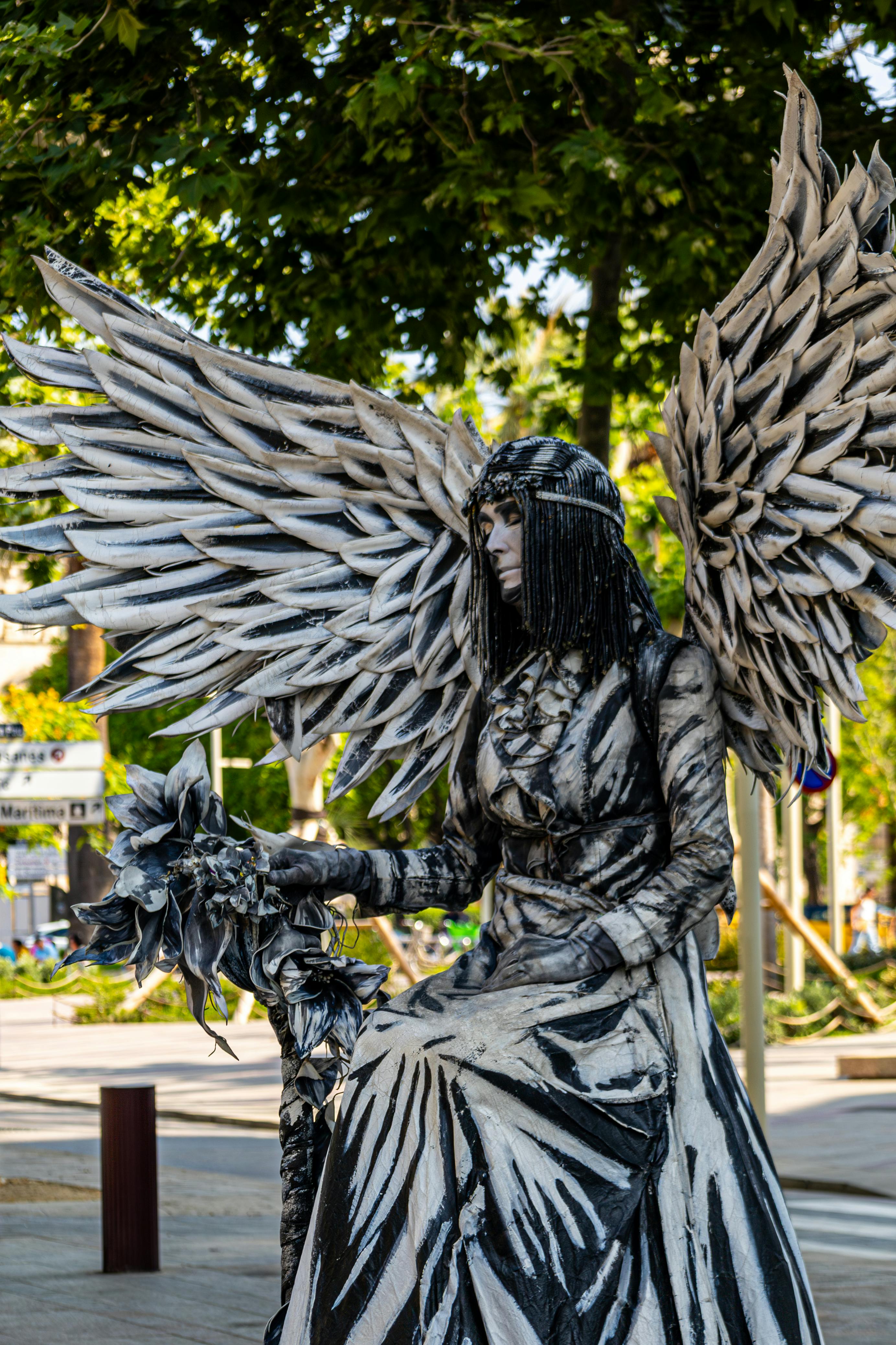 Ücretsiz Canlı bir şehir parkında melek heykeli kostümü giymiş sokak sanatçısı. Stok Fotoğraflar