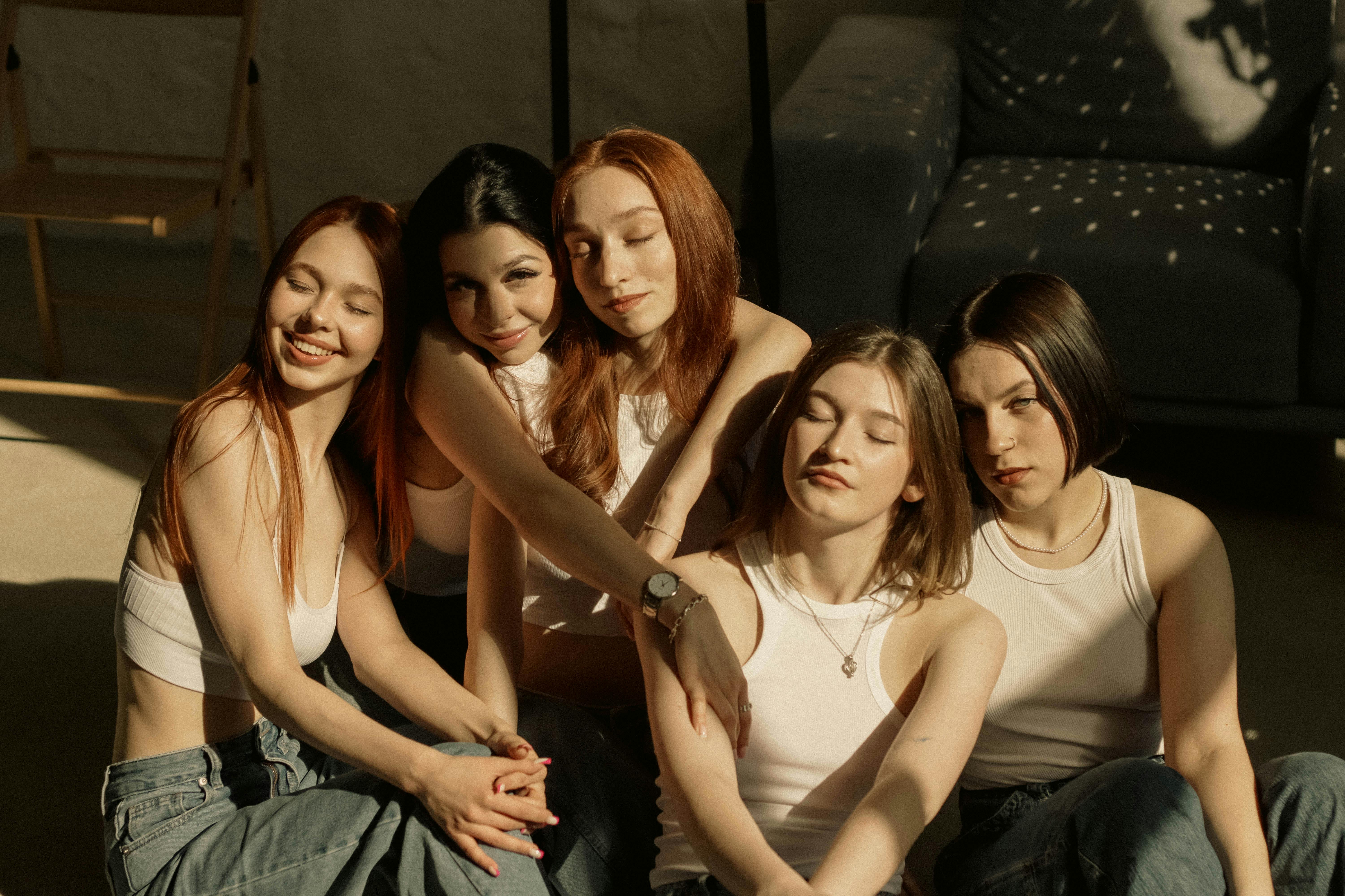 Five young women enjoying a sunlit moment indoors, showcasing friendship and relaxation.
