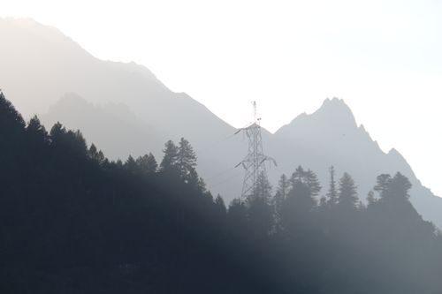 Free Silhouette of mountains and trees with a power line tower at dawn. Stock Photo
