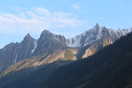 Free A breathtaking view of a majestic mountain range with snowy peaks under a clear blue sky at sunrise. Stock Photo