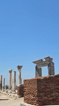 Explore ancient stone columns and brick walls under a vivid blue sky.