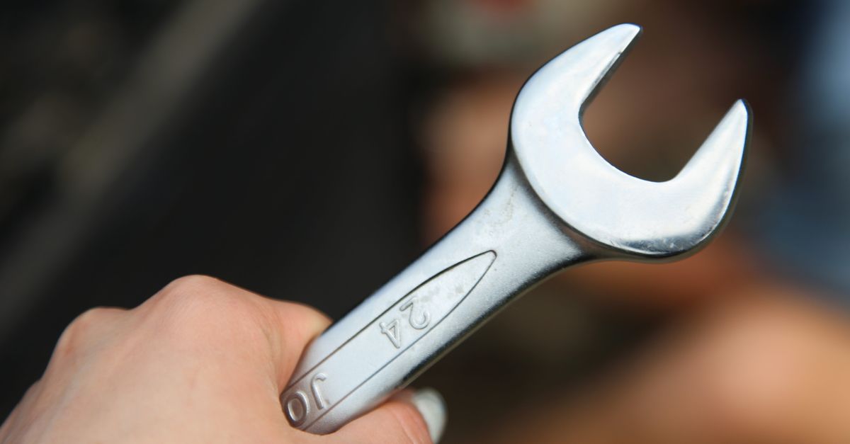 A hand holding a shiny metal wrench, ideal for repair and mechanic themed visuals.