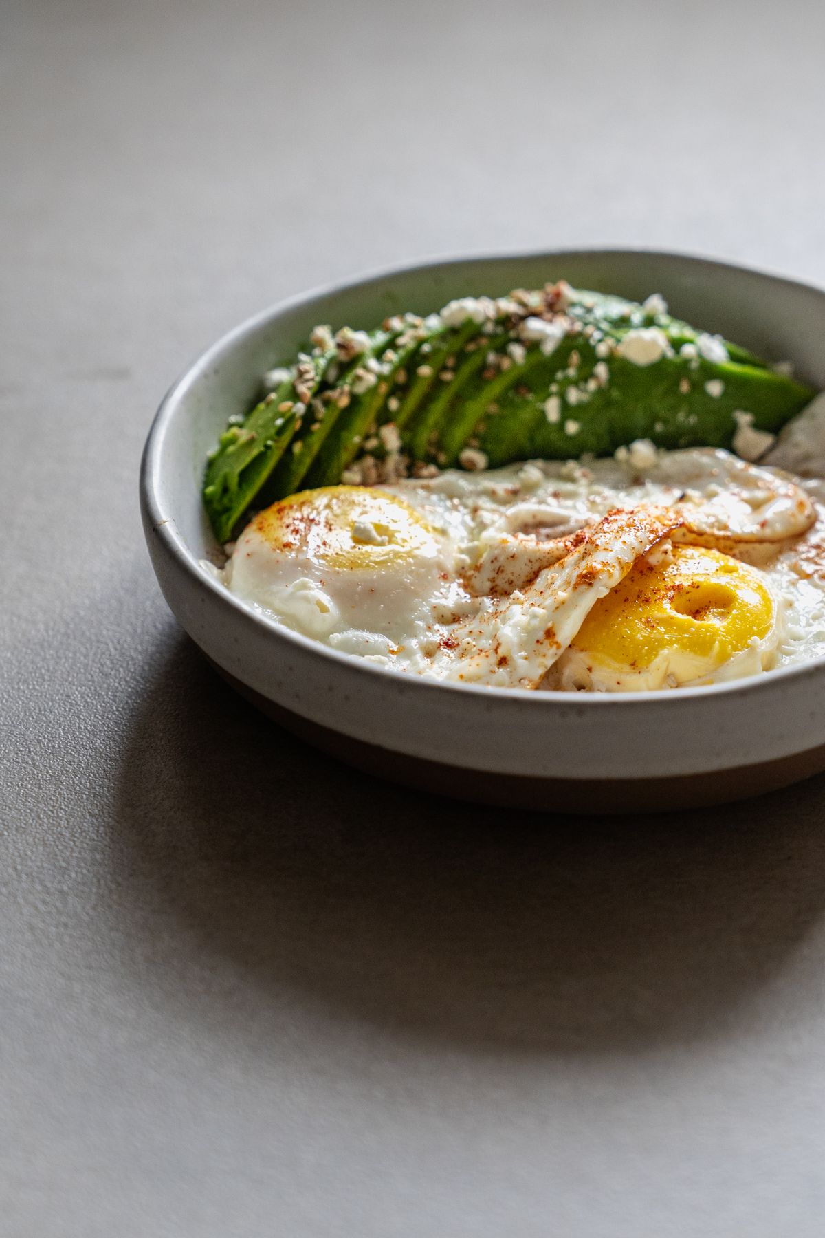 Breakfast with sliced avocado, fried eggs, and feta cheese