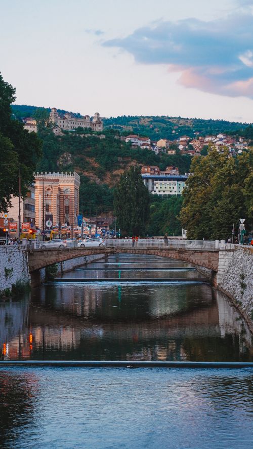 Free Picturesque scene of Sarajevo's Vijećnica by the river at twilight, capturing the city's historic architecture. Stock Photo