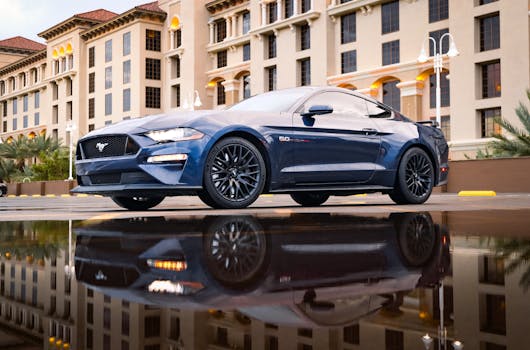 A sleek blue sports car parked in front of luxurious architecture with reflective surface.