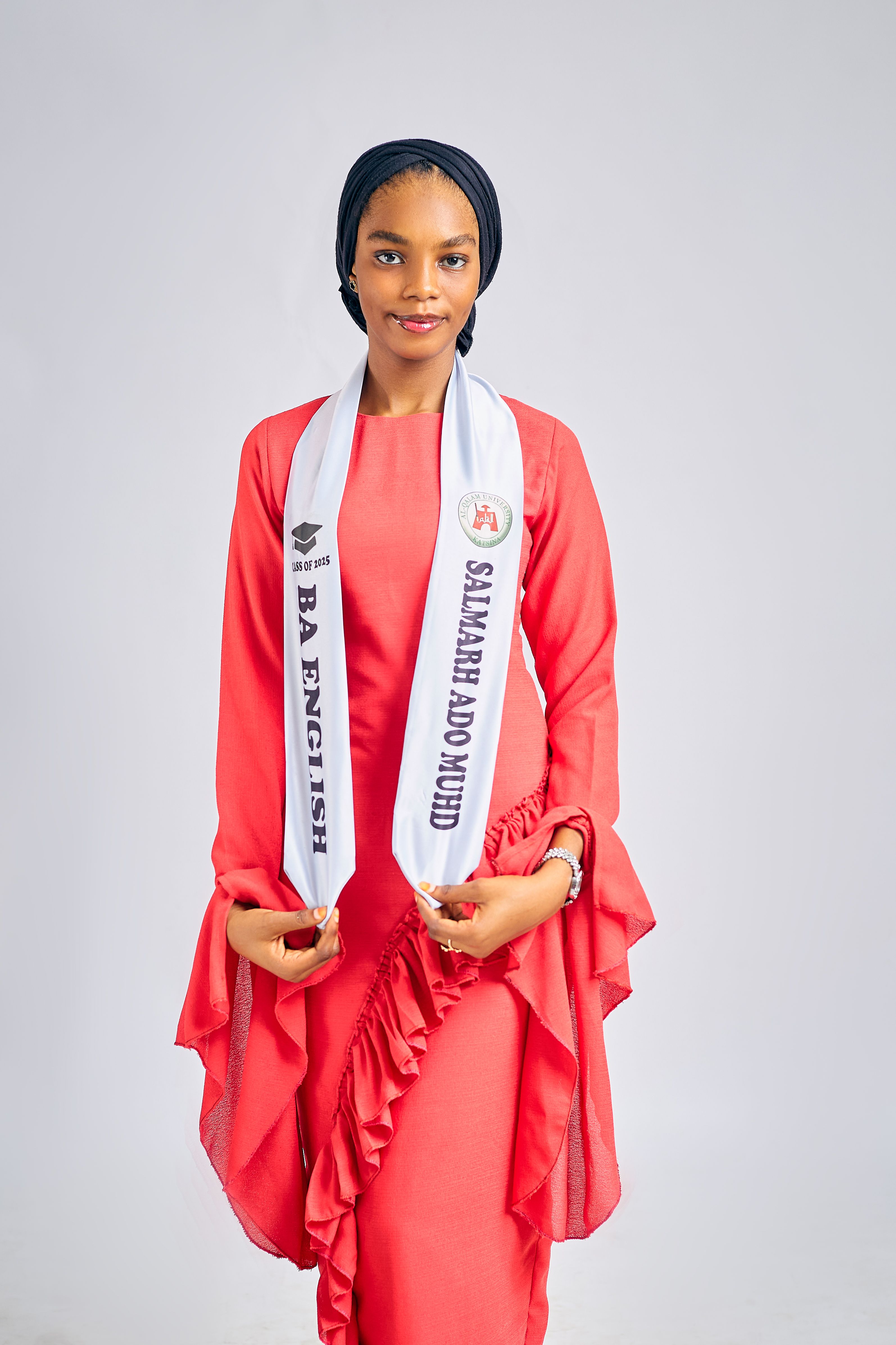 Confident female graduate celebrating achievement in vibrant red outfit.