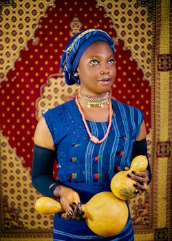 Woman in vibrant African attire holding traditional gourds against a decorative backdrop.