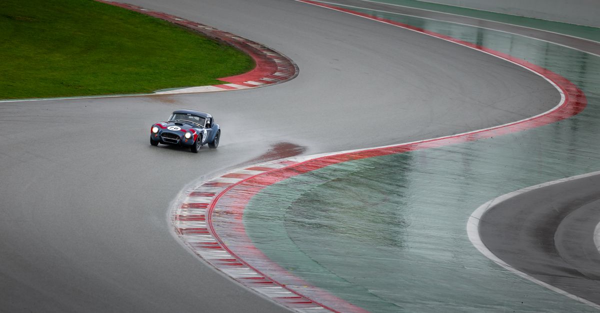 Vintage sports car navigating a wet racetrack curve with speed and agility.