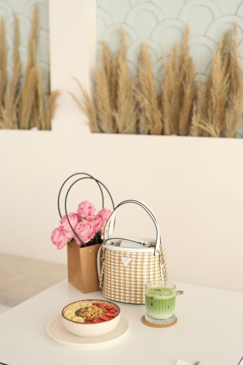 Free Stylish cafe table with designer bag, pink roses, matcha latte, and scenic decor. Stock Photo
