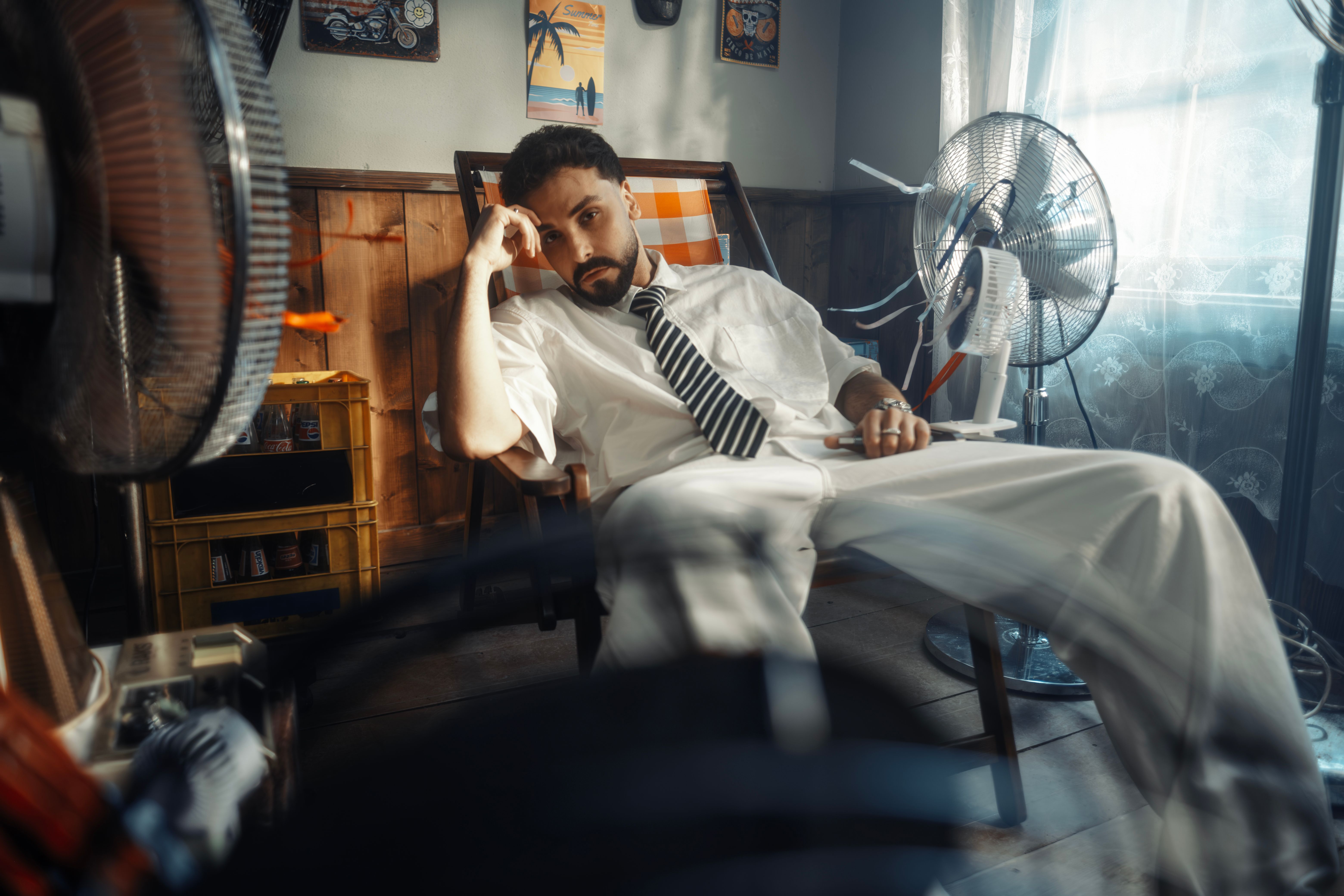 Man Relaxing Indoors with Cooling Fans During Summer · Free Stock Photo
