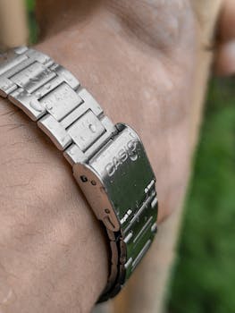 Macro shot of a watch on a wrist with water droplets, highlighting design and texture.