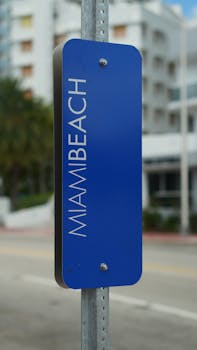 Vertical blue city sign with 'MIAMI BEACH' text, capturing urban Miami Beach streetscape.