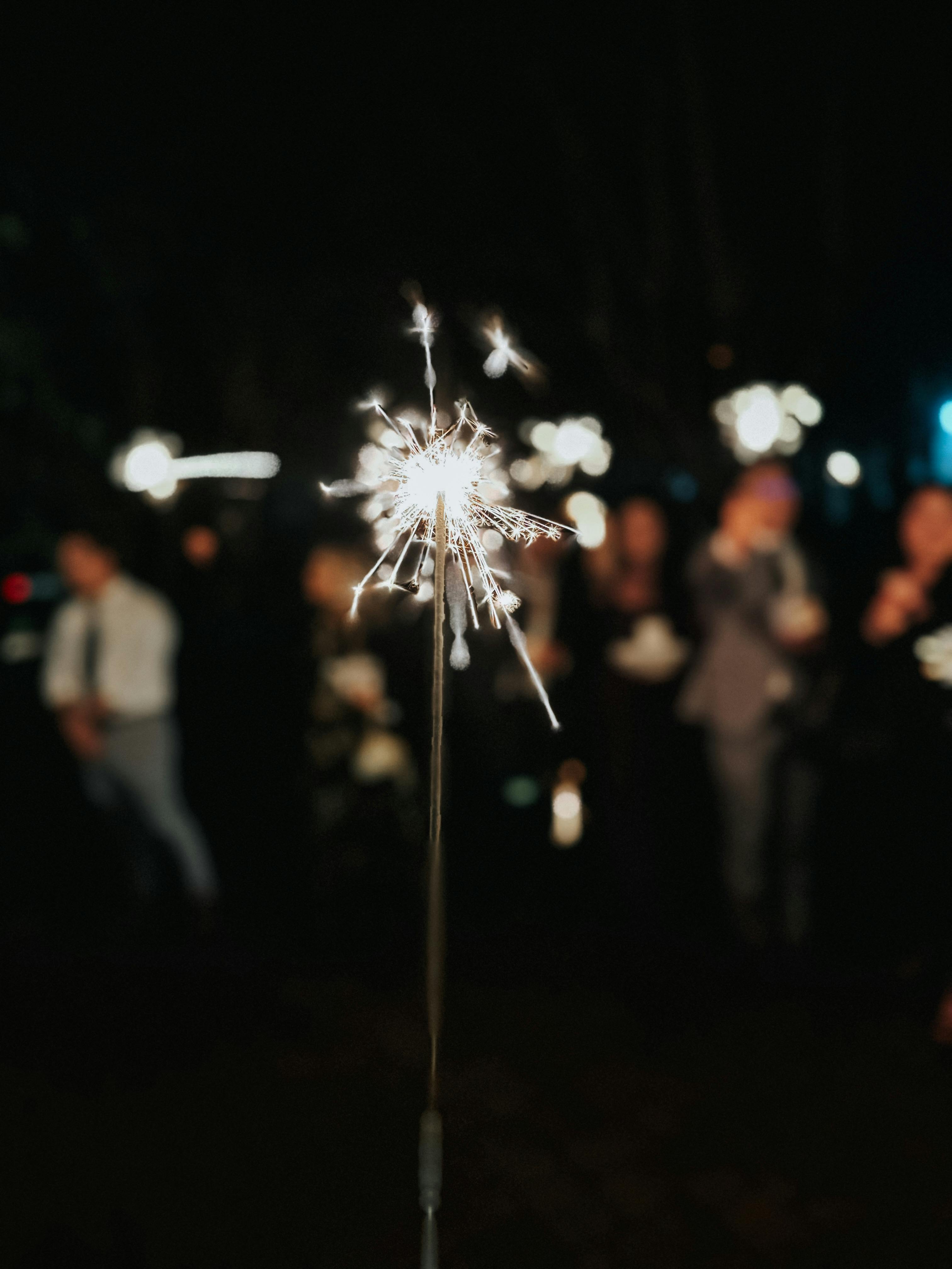A vibrant sparkler lights up a night celebration with people in the background in Tampa, FL.