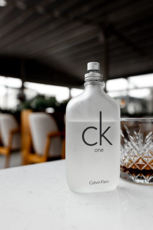 Free Sophisticated CK One perfume bottle with glass, set on outdoor cafe table. Stock Photo