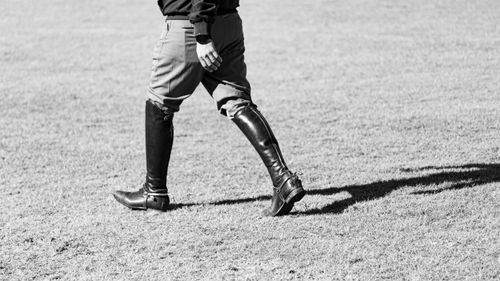 Free Monochrome image of a person walking on grass wearing equestrian attire and boots. Stock Photo