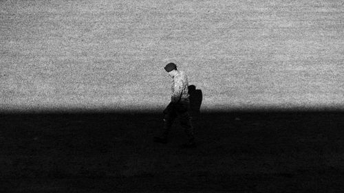 Free Black and white image of a soldier walking in a shadowed area. Stock Photo