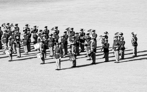 Free A black and white image of a military marching band performing outdoors, featuring uniformed members playing instruments. Stock Photo