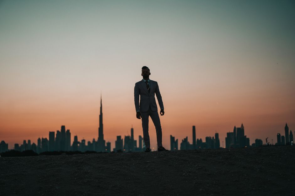 A man in formal wear standing against the Dubai skyline at twilight, showcasing elegance and style. A man in formal wear standing against the Dubai skyline at twilight, showcasing elegance and style.