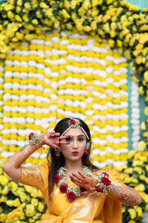 Free Woman in yellow sari adorned with floral jewelry, celebrating with henna. Stock Photo