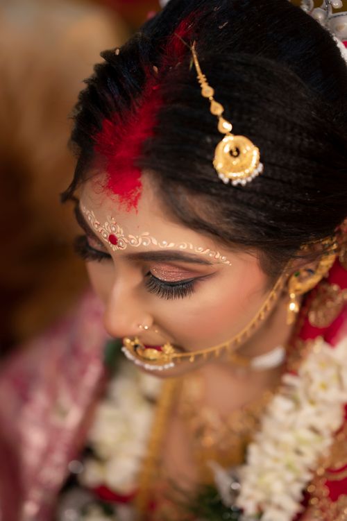 Free Detailed close-up portrait of a traditional Indian bride adorned with gold jewelry. Stock Photo