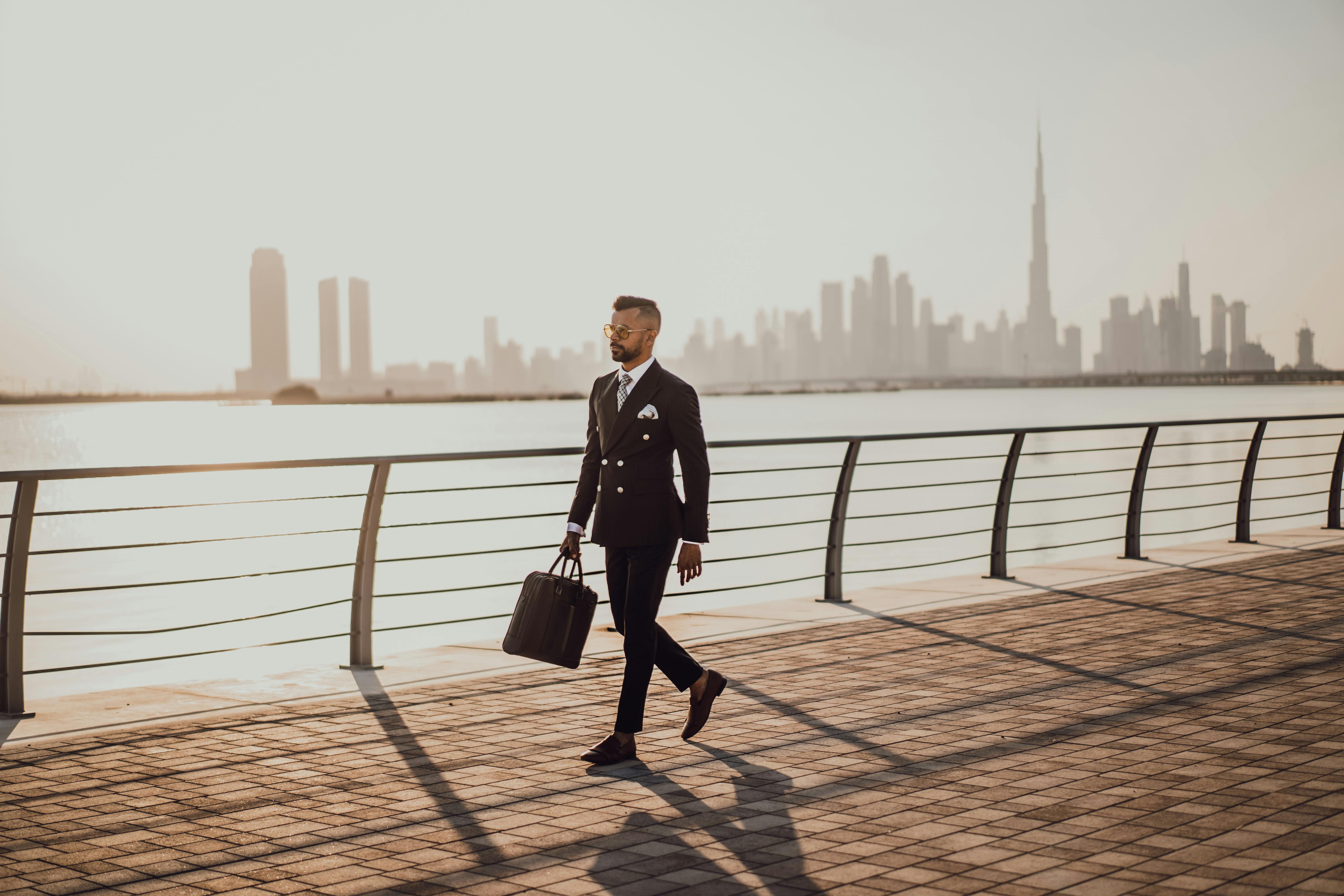 Man walking on pavement while holding a bag. | Photo: Pexels