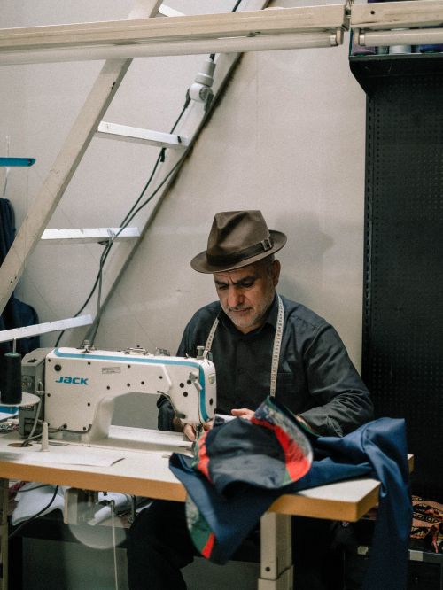 Free Craftsman sewing in tailor shop, focusing on intricate garment work. Stock Photo