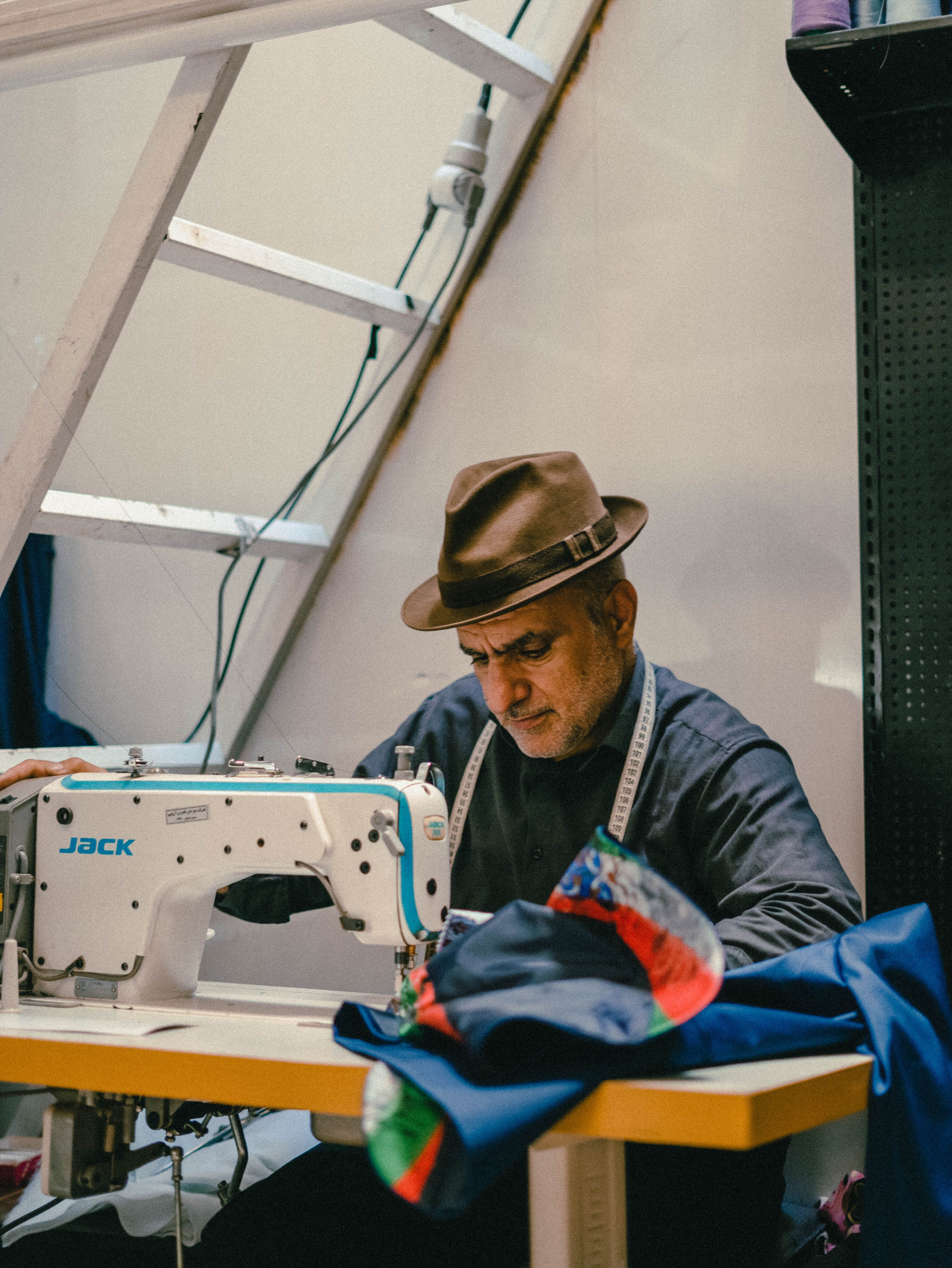 Experienced tailor focused on sewing fabric with a modern machine in a workshop.