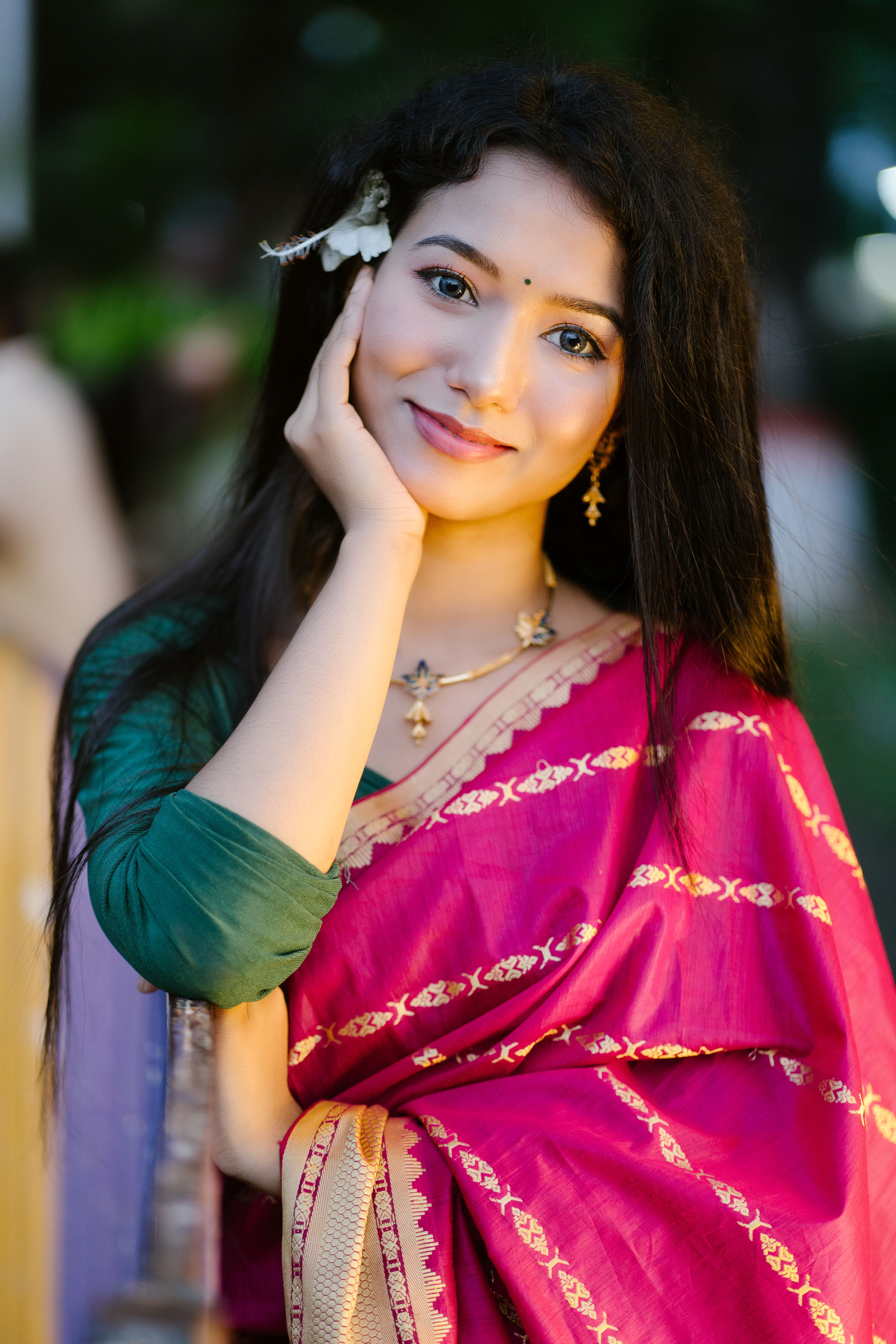A beautifully dressed woman smiling confidently in a traditional pink sari, captured outdoors.