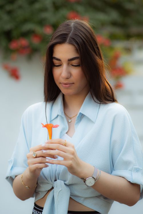 Free A serene portrait of a young woman holding a flower, set in a summer backdrop in Golestan Province, Iran. Stock Photo