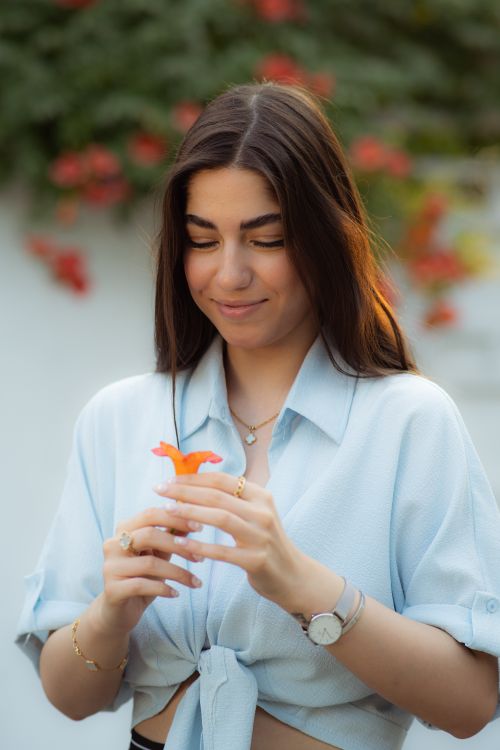 Free A woman holding a vibrant orange flower outdoors in Gorgan, Iran. Captured on a sunny day. Stock Photo
