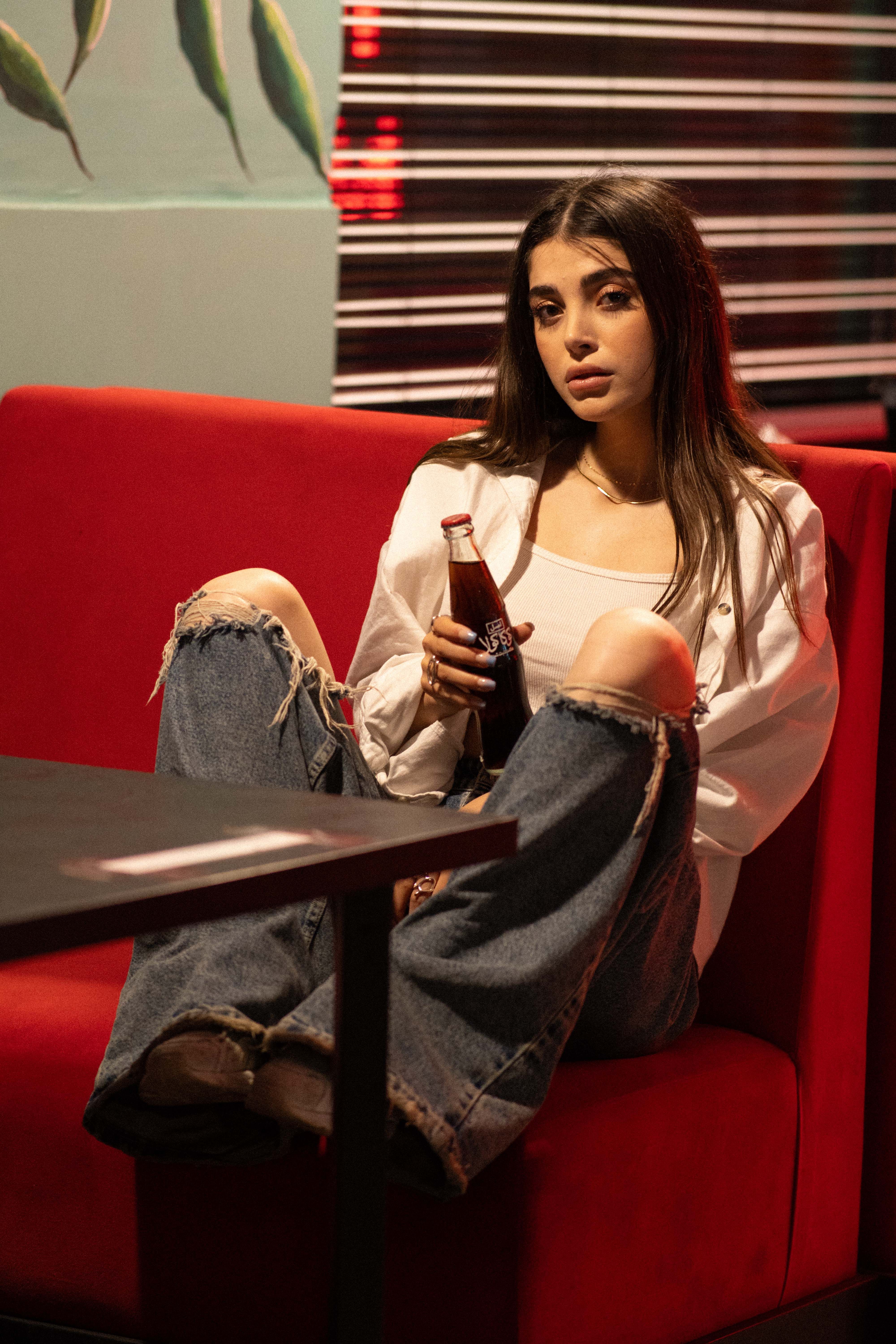 Stylish portrait of a woman enjoying a soda in a chic cafe interior setting.