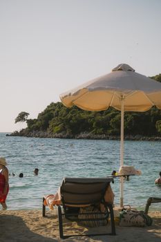 Relaxing summer scene at Ksamil beach, Albania, featuring umbrellas and serene sea views.