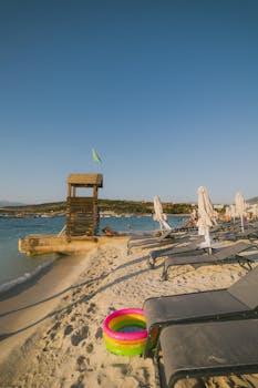 Relaxing beach scene at Ksamil, Albania with clear skies and lounge chairs.