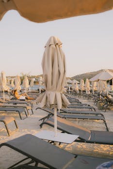 Relaxing beachfront scene at sunset in Ksamil, Albania with empty loungers and umbrellas.