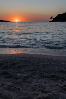 Peaceful beach sunset at Ksamil, Albania, with serene waves and vivid sky.