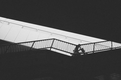 Free Black and white photo of a person on a walkway bridge with strong contrast. Stock Photo