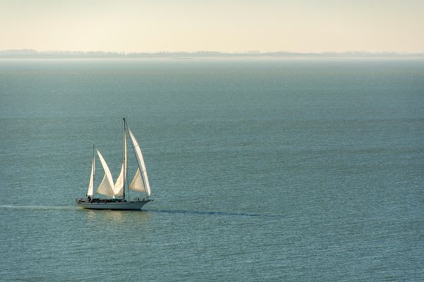 A sailing ship under white sails on a calm sea