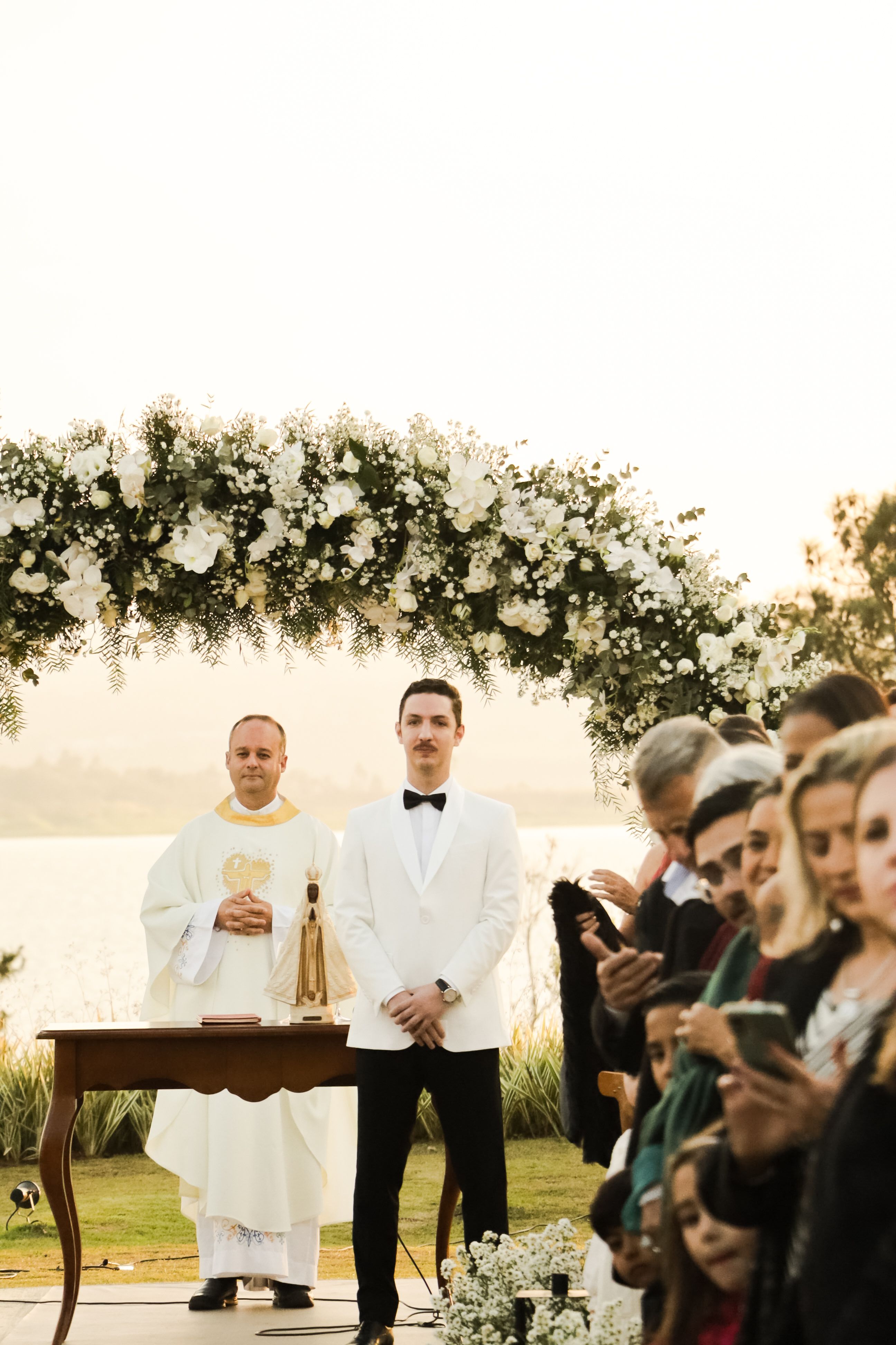 A beautiful outdoor wedding ceremony beside a lake with guests and floral decorations in São Paulo.